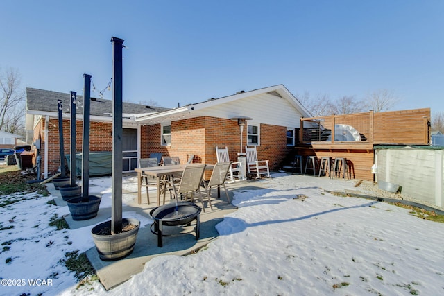 snow covered house with an outdoor fire pit and an outdoor bar