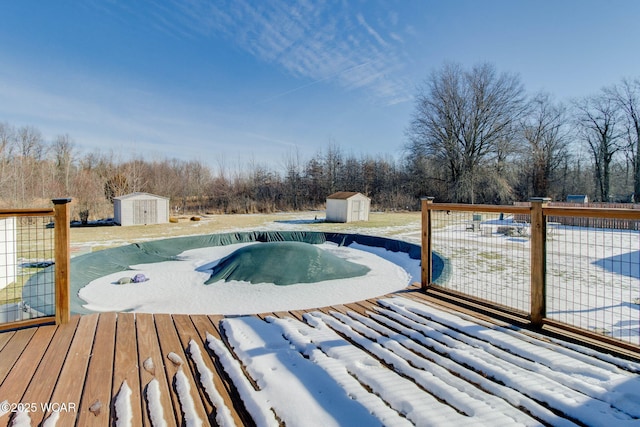 snow covered pool featuring a deck and a storage shed