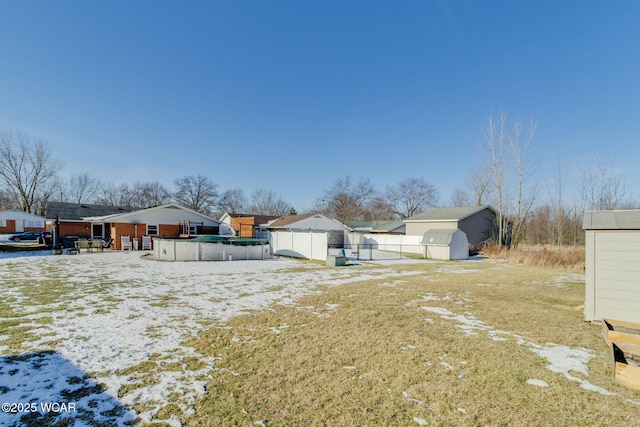 yard layered in snow featuring a storage shed and a covered pool