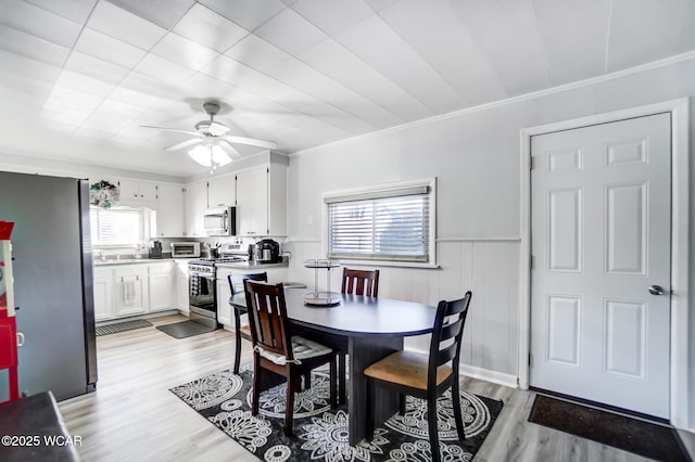 dining space featuring ornamental molding, a wealth of natural light, and light hardwood / wood-style flooring