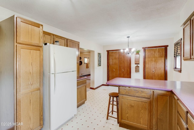 350 W Highland Ave, Ada, OH 45810 - kitchen featuring freestanding refrigerator, a peninsula, a chandelier, pendant lighting, and a breakfast bar