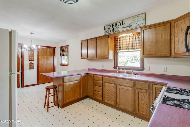 350 W Highland Ave, Ada, OH 45810 - kitchen featuring freestanding refrigerator, a peninsula, and brown cabinets
