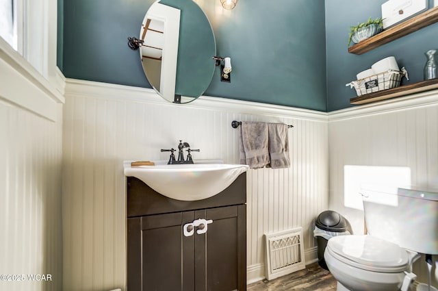 bathroom with hardwood / wood-style flooring, vanity, toilet, and radiator