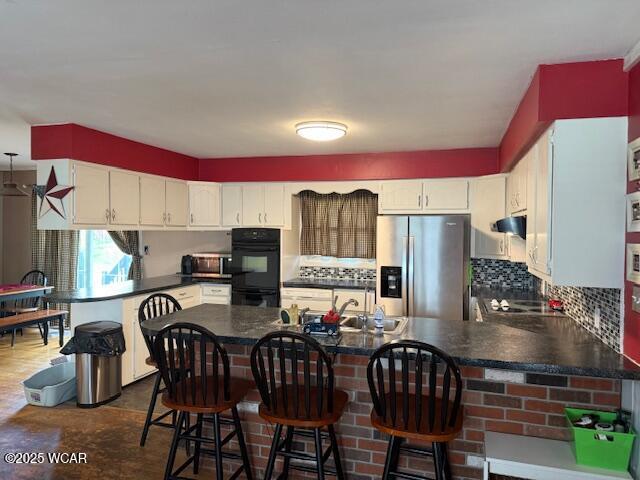 kitchen featuring a peninsula, dark countertops, backsplash, and appliances with stainless steel finishes