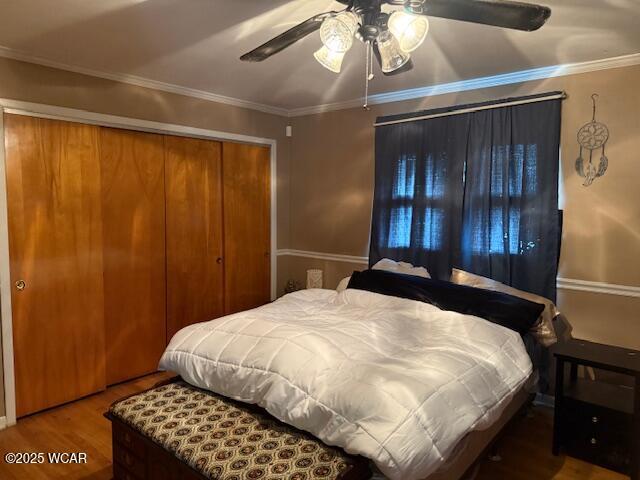 bedroom featuring a ceiling fan, crown molding, wood finished floors, and a closet