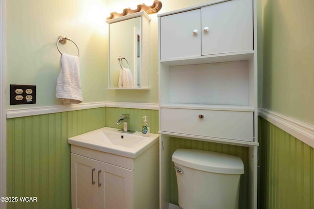 bathroom featuring wainscoting, toilet, wood walls, and vanity