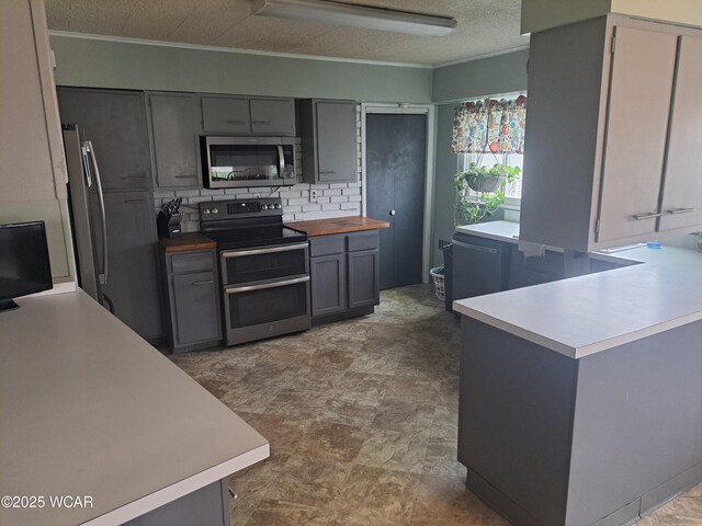 kitchen featuring wood counters, stainless steel appliances, ornamental molding, and backsplash