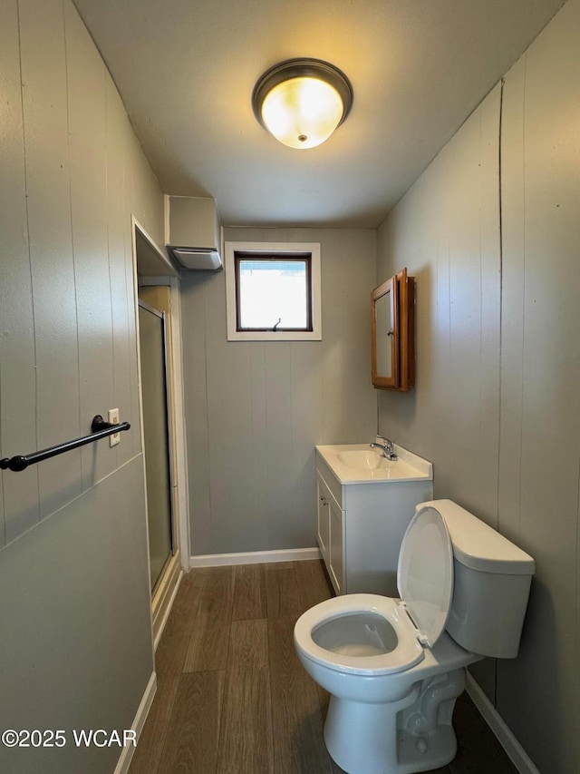 bathroom with hardwood / wood-style flooring, toilet, a shower with door, and vanity