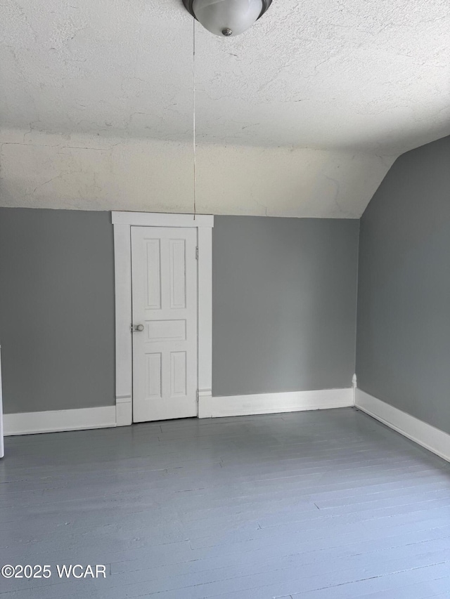 bonus room with a textured ceiling, dark wood-type flooring, and lofted ceiling