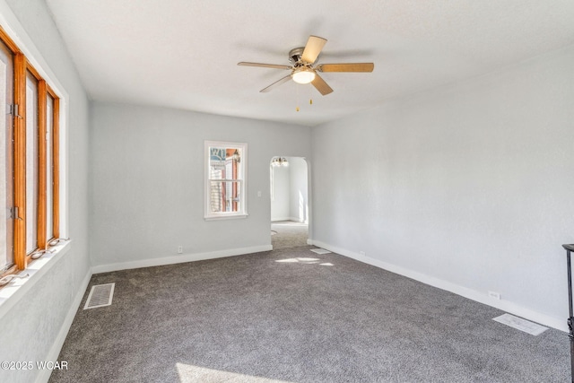 carpeted empty room featuring visible vents, arched walkways, baseboards, and a ceiling fan