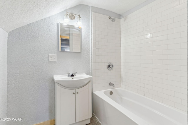 bathroom with a textured ceiling, a textured wall, shower / bath combination, vanity, and vaulted ceiling