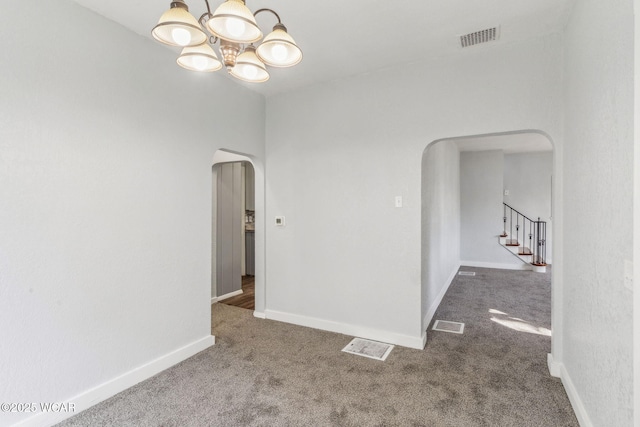 empty room featuring arched walkways, visible vents, baseboards, and carpet floors