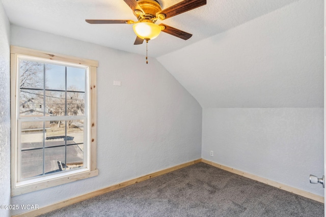 additional living space with baseboards, carpet floors, ceiling fan, vaulted ceiling, and a textured wall