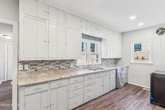 kitchen with visible vents, a sink, tasteful backsplash, stainless steel dishwasher, and dark wood finished floors