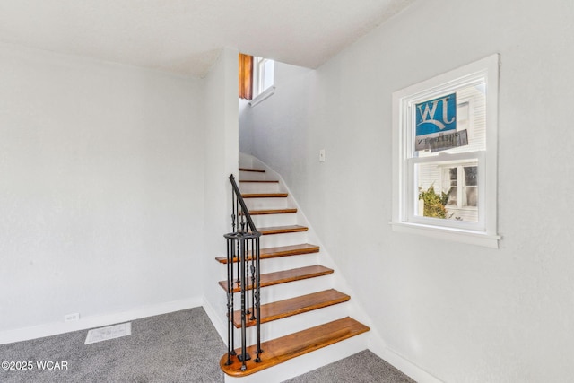 staircase with a healthy amount of sunlight, baseboards, and carpet