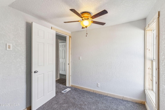 unfurnished bedroom with visible vents, carpet flooring, a textured ceiling, and a textured wall