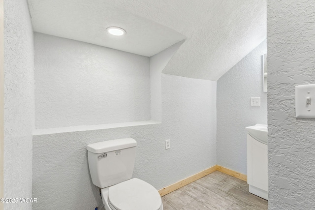 half bathroom with toilet, a textured wall, baseboards, and a textured ceiling