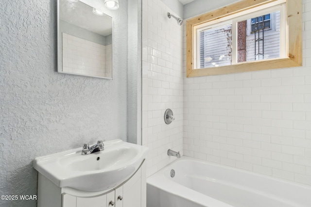 bathroom with vanity, bathtub / shower combination, and a textured wall