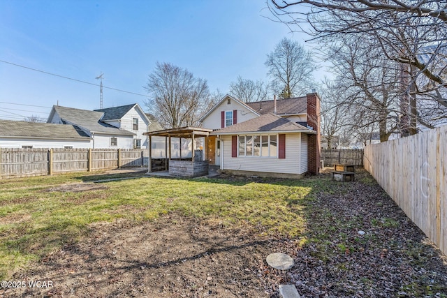 back of house featuring a lawn, a fenced backyard, and a chimney