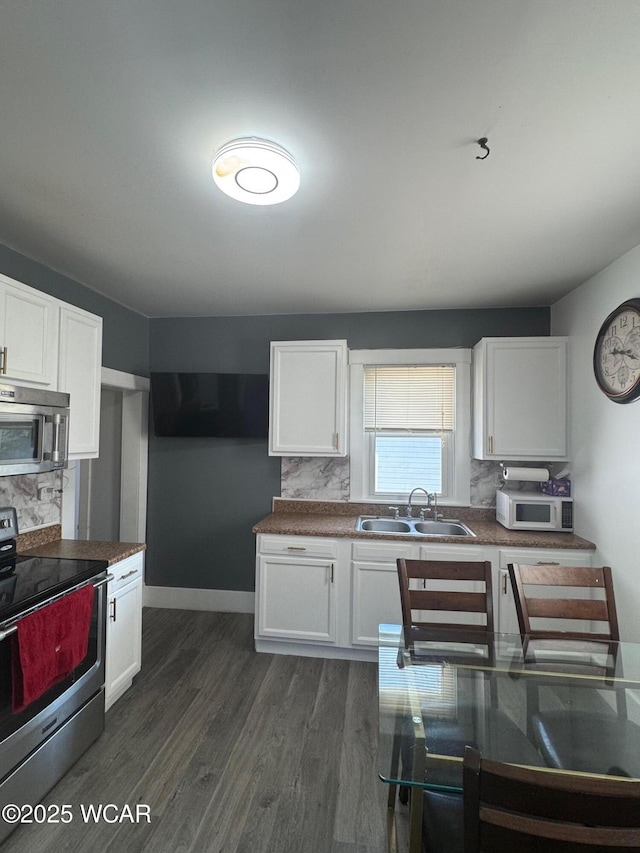 110 Heisel St, Kenton, OH 43326 - kitchen with stainless steel appliances, decorative backsplash, white cabinets, and dark wood-style flooring