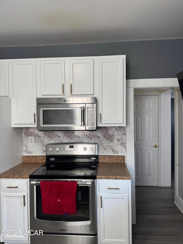 110 Heisel St, Kenton, OH 43326 - kitchen with appliances with stainless steel finishes, white cabinetry, dark countertops, dark wood-style floors, and decorative backsplash