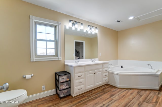 bathroom featuring vanity, a bath, hardwood / wood-style flooring, and toilet