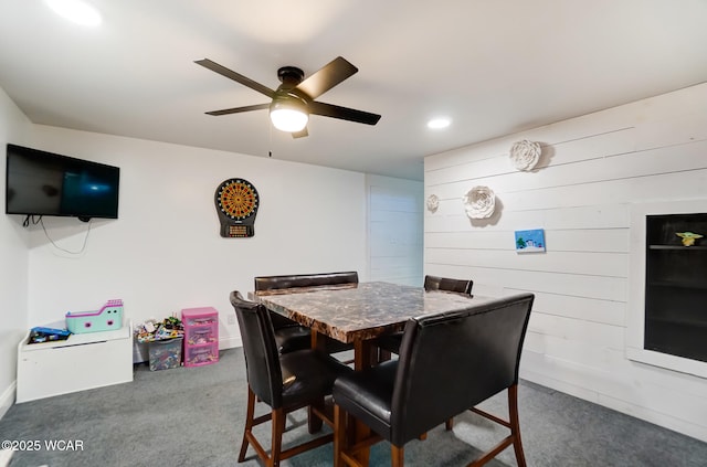 dining area featuring ceiling fan, carpet floors, and wood walls