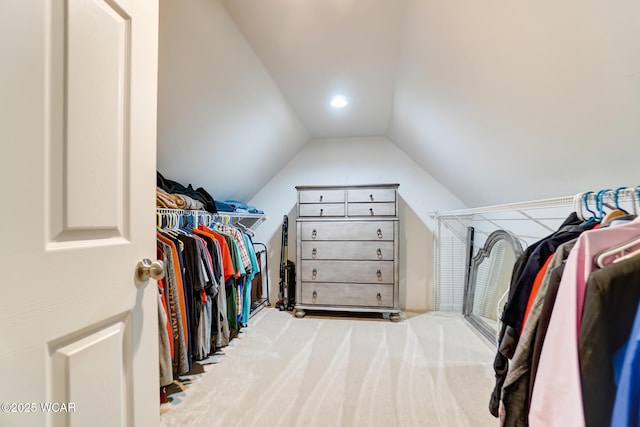 walk in closet with vaulted ceiling and light colored carpet