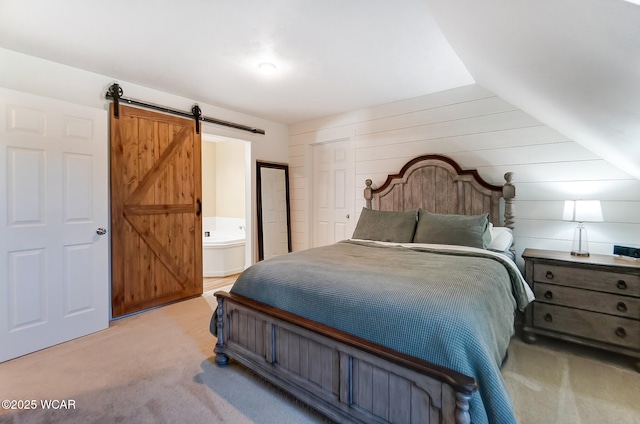 carpeted bedroom featuring connected bathroom, a closet, and a barn door