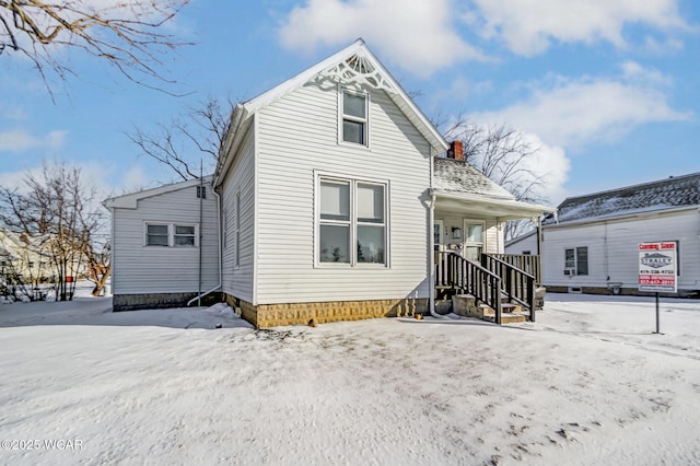 snow covered back of property with covered porch