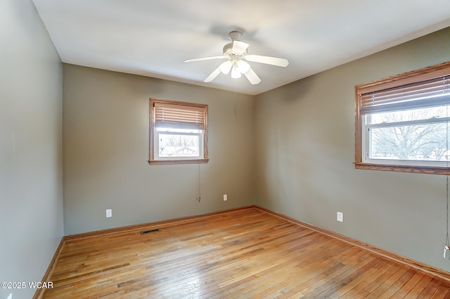 spare room with light wood-style floors, a healthy amount of sunlight, and visible vents