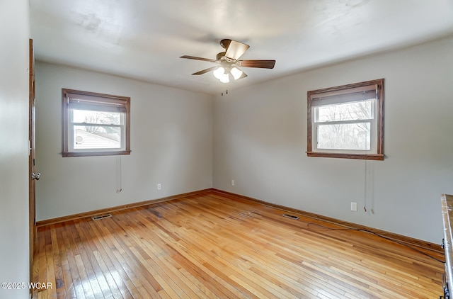 unfurnished room with visible vents, plenty of natural light, and wood-type flooring