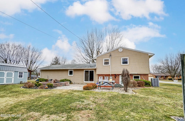 rear view of house featuring brick siding, a patio area, a lawn, and an outdoor structure