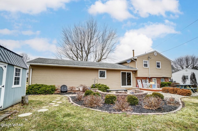 rear view of property with a lawn, a fire pit, and an outdoor structure