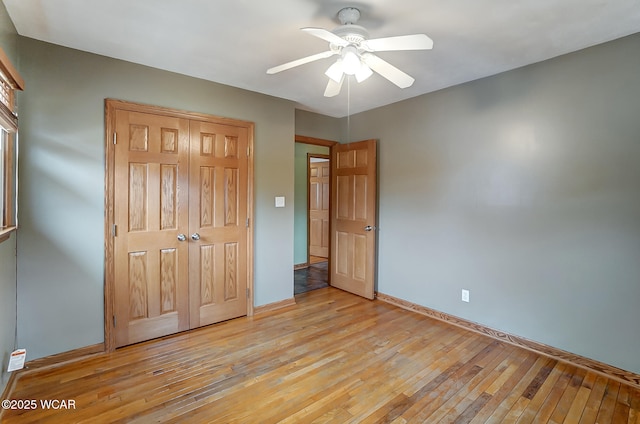 unfurnished bedroom with a closet, ceiling fan, light wood-type flooring, and baseboards