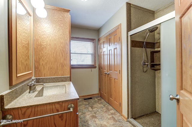 bathroom with vanity, baseboards, visible vents, and a stall shower