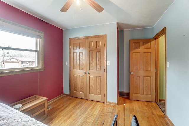 unfurnished bedroom with a closet, ceiling fan, light wood-type flooring, and baseboards