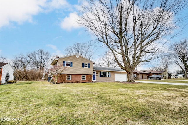 split level home with brick siding, a front lawn, a chimney, a garage, and driveway