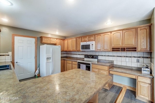 kitchen with white appliances, wood finished floors, a peninsula, and backsplash