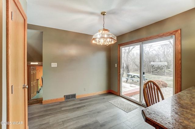 dining room featuring a chandelier, visible vents, baseboards, and wood finished floors