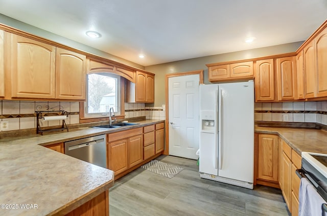 kitchen featuring decorative backsplash, white appliances, light wood-style floors, and a sink