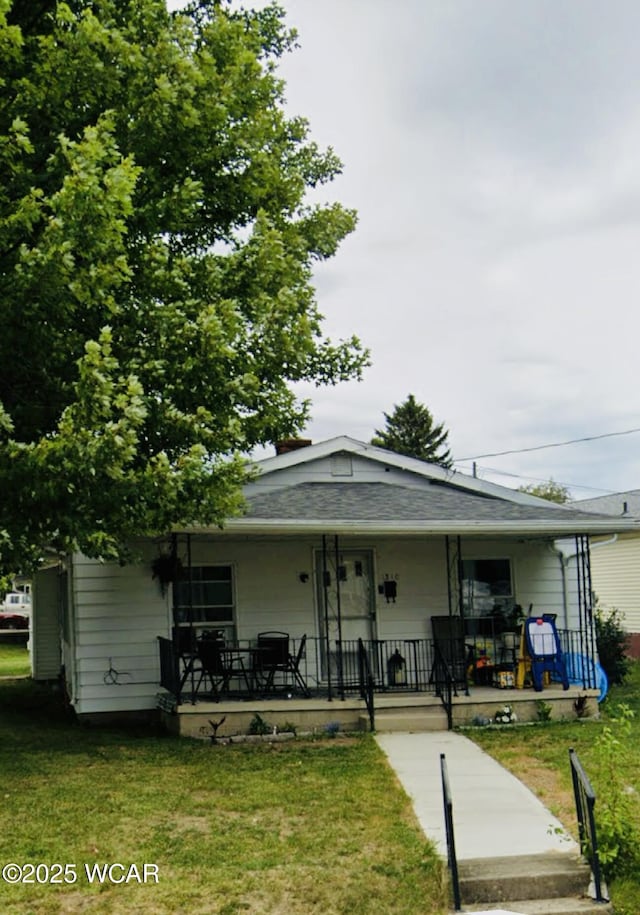 view of front of property featuring a porch, roof with shingles, and a front yard
