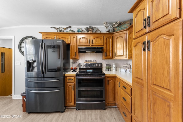 2435 Bible Rd, Lima, OH 45801 - kitchen with appliances with stainless steel finishes, under cabinet range hood, light countertops, light wood finished floors, and a textured ceiling