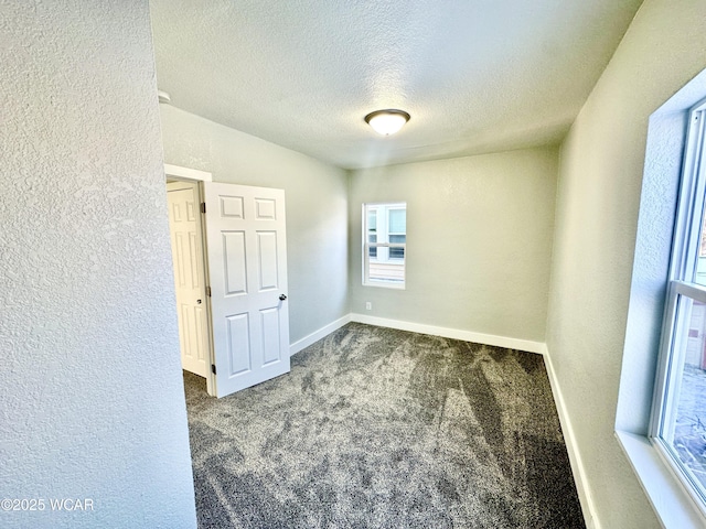 unfurnished room with dark colored carpet and a textured ceiling