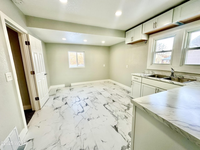 kitchen with a healthy amount of sunlight, sink, and white cabinets