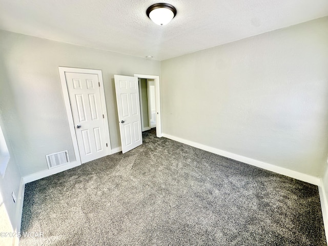 unfurnished bedroom featuring a textured ceiling, a closet, and dark colored carpet