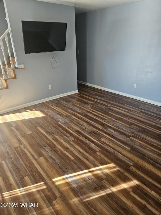 unfurnished living room featuring dark wood-style floors, stairs, and baseboards