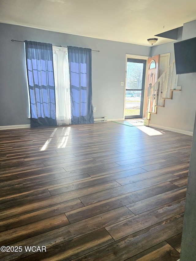 unfurnished living room featuring a baseboard heating unit, dark wood-style flooring, stairway, and baseboards