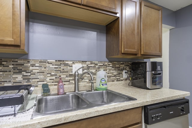 kitchen featuring dishwashing machine, a sink, light countertops, and decorative backsplash