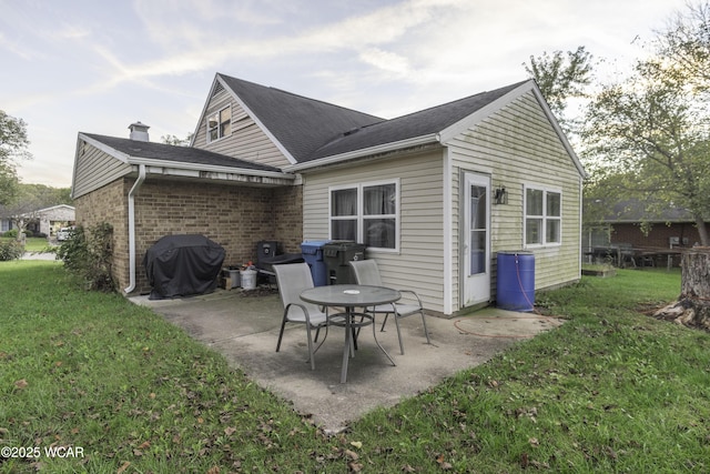 rear view of house featuring brick siding, a patio, and a lawn